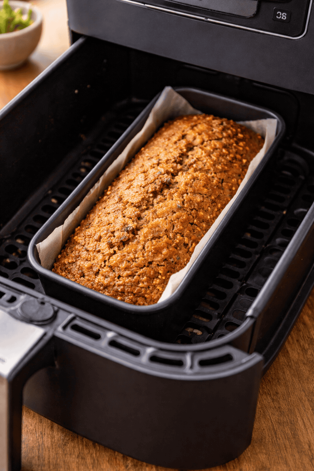 Karottenkuchen in Kastenform direkt in der Heißluftfritteuse beim Backen, goldbraune Oberfläche mit sichtbaren Karottenstückchen