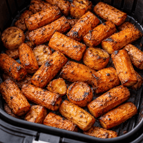 Gleichmäßig geschnittene Karotten im schwarzen Airfryer-Korb, goldbraun geröstet mit sichtbaren Röstaromen und Gewürzen