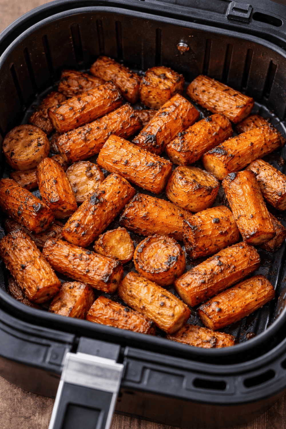 Gleichmäßig geschnittene Karotten im schwarzen Airfryer-Korb, goldbraun geröstet mit sichtbaren Röstaromen und Gewürzen