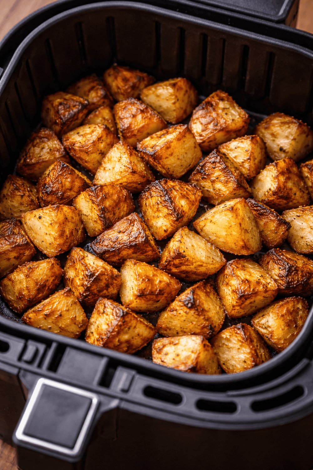 Knusprige Kartoffelspalten im Airfryer-Korb, gleichmäßig goldbraun gebacken und perfekt gewürzt