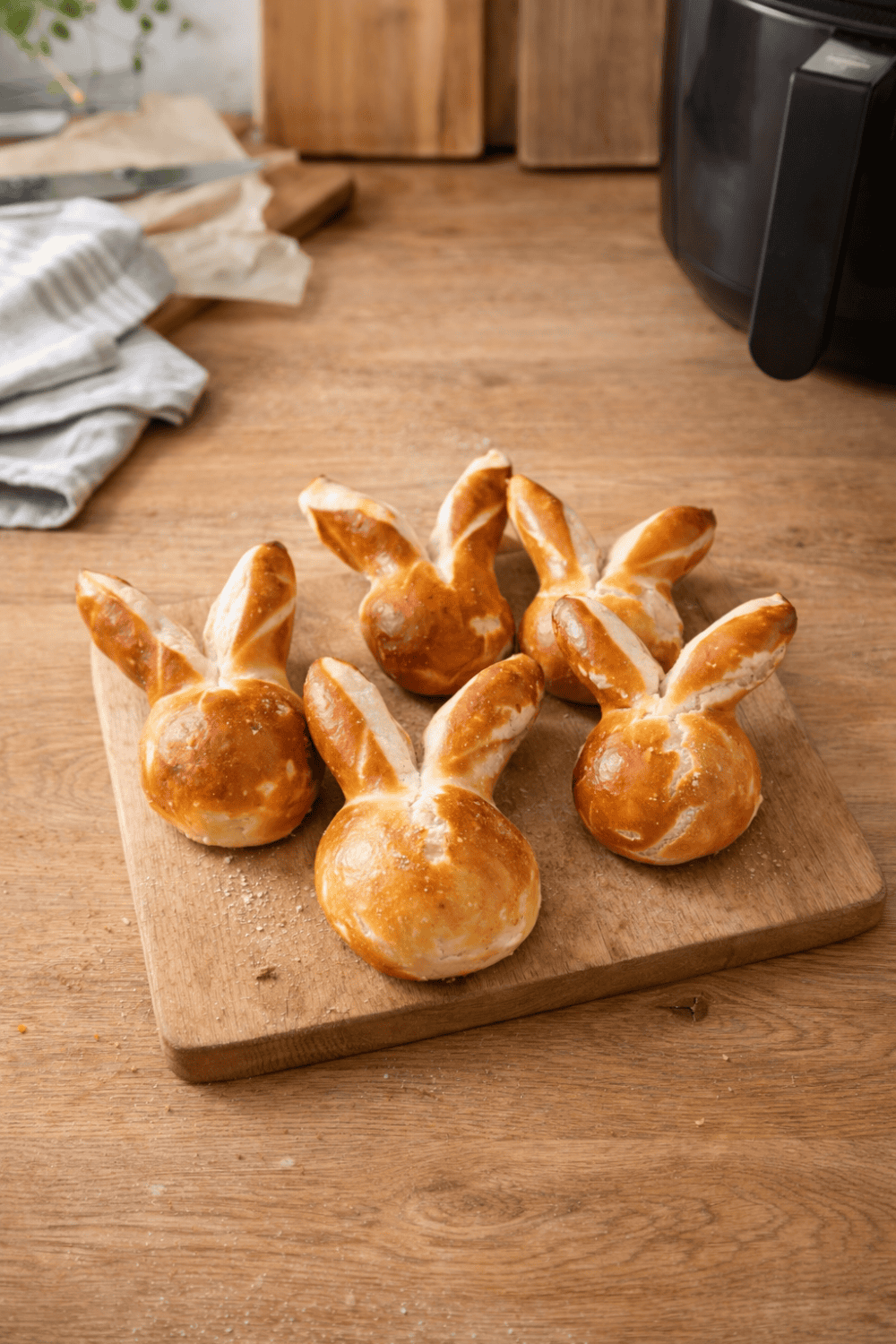 Goldbraune Laugen-Osterhasen aus der Heißluftfritteuse auf Holzschneidebrett