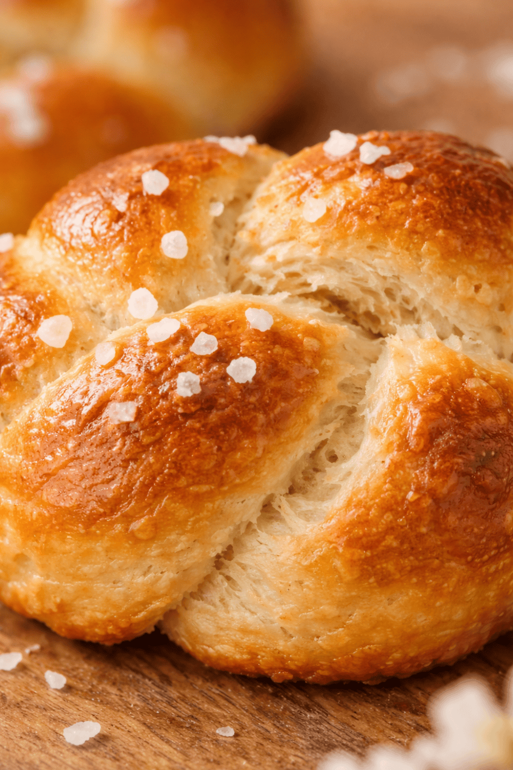 Nahaufnahme eines aufgerissenen Mini-Hefezopfs, fluffige luftige Krume sichtbar, goldbraune Kruste mit Hagelzucker, perfekt gebacken