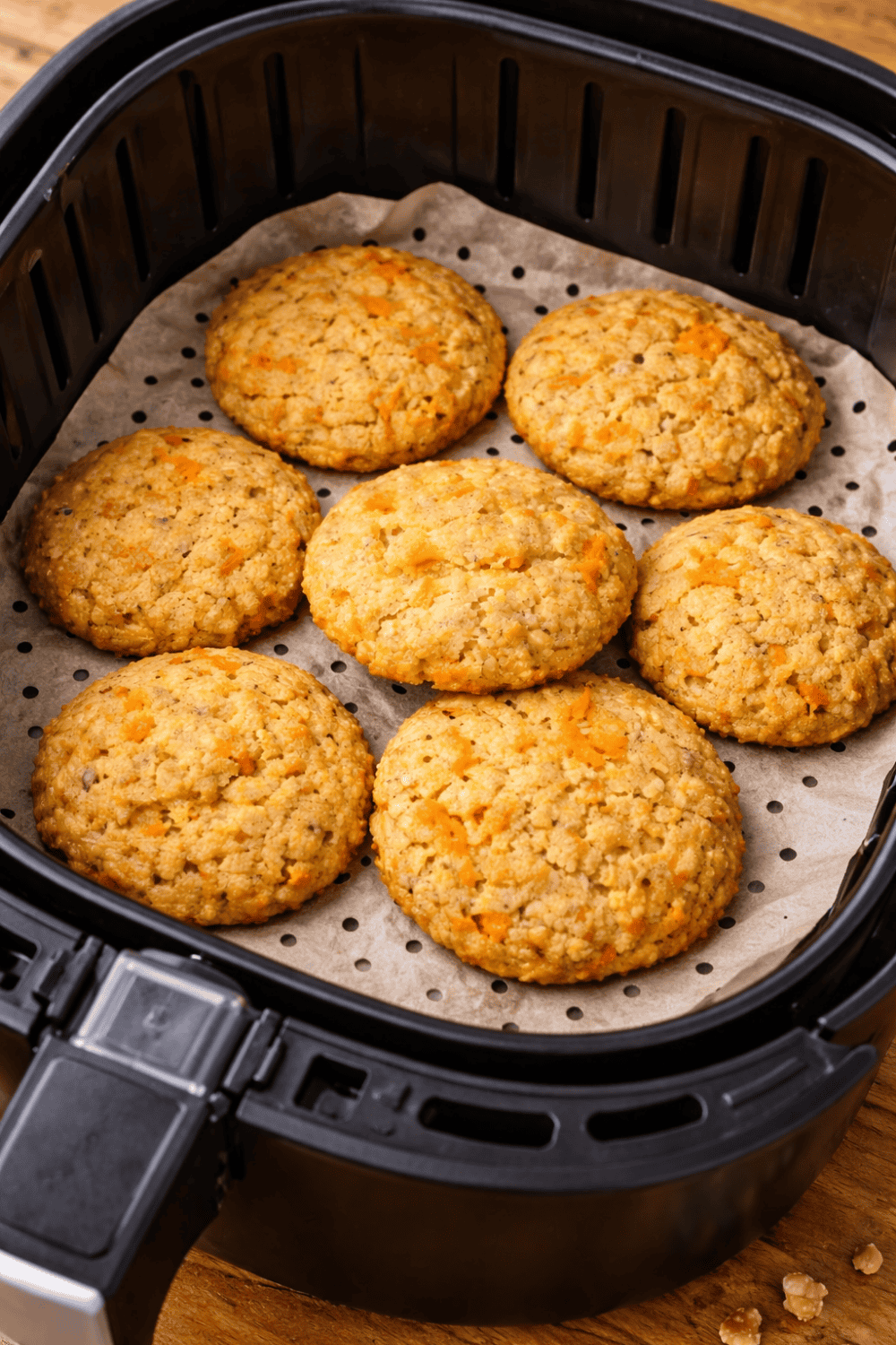 Goldgelbe Karottenkekse im Airfryer-Korb auf perforiertem Backpapier, frisch gebacken bei 160 Grad