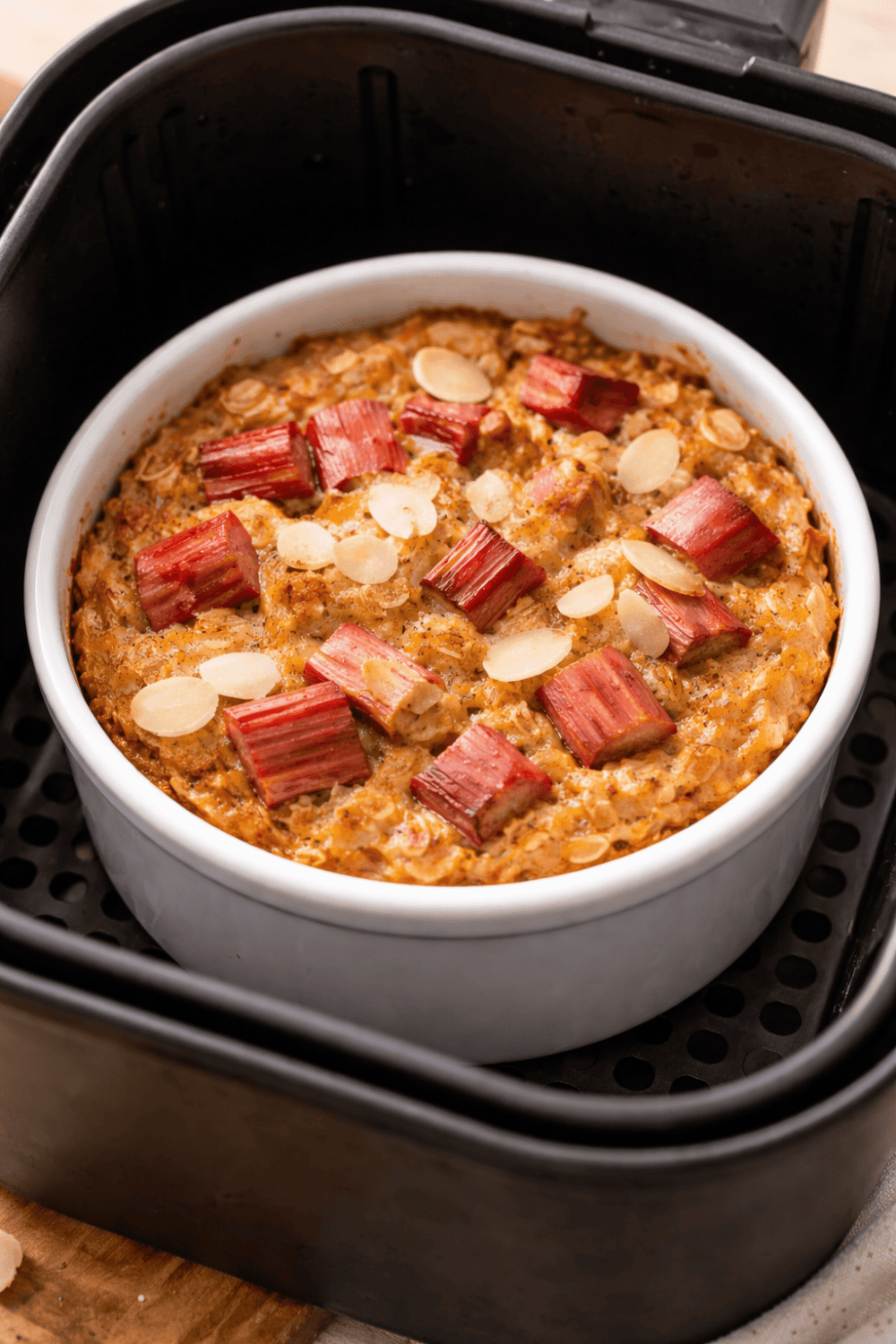 Rhabarber Baked Oats in weißer Auflaufform direkt im Korb der Heißluftfritteuse – fertig gebacken mit goldbrauner Oberfläche