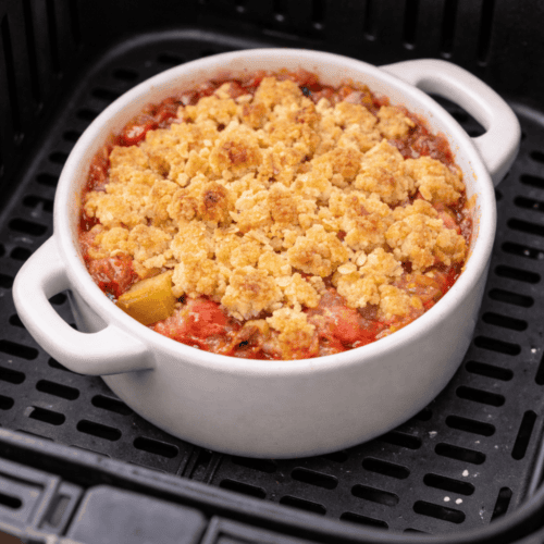 Rhabarber Crumble in weißer Auflaufform im Airfryer-Korb der Heißluftfritteuse mit knusprigen Streuseln beim Backen