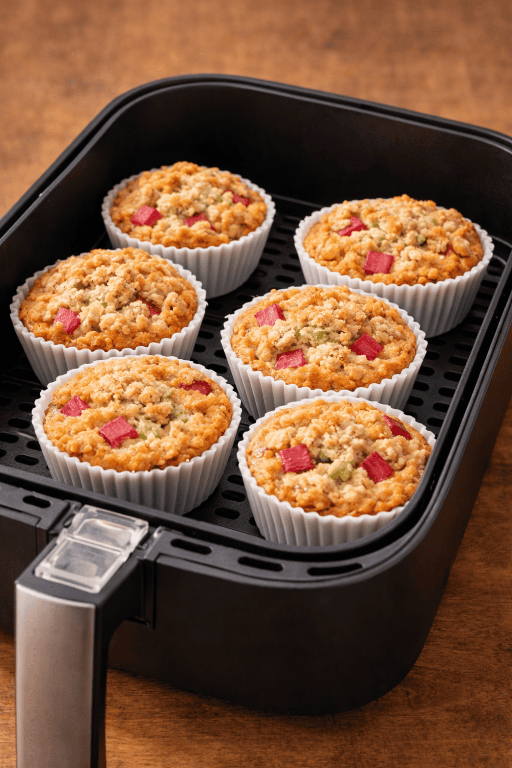 Sechs Rhabarber-Streusel-Muffins in weißen Silikonförmchen frisch gebacken im Airfryer-Korb