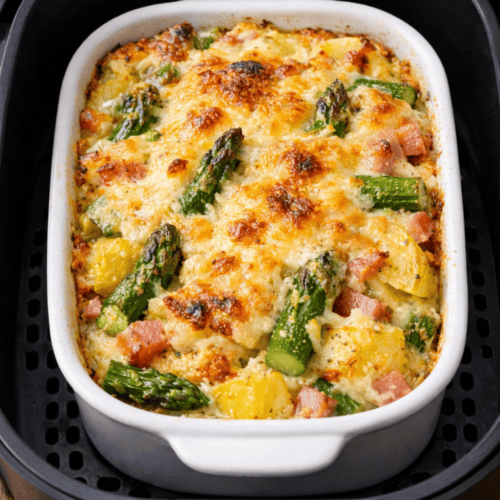 Spargel-Auflauf in kleiner Auflaufform im Airfryer-Korb, überbacken mit Käse, Kartoffeln und grünem Spargel sichtbar